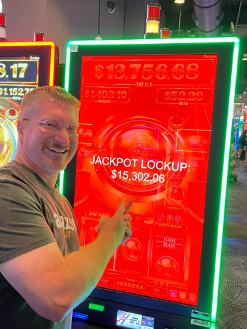 Aaron A. standing in front of machine with $15,302.06 jackpot win.