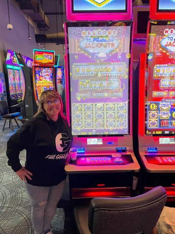 Amy R. standing in front of machine with $13,084.58 jackpot win.