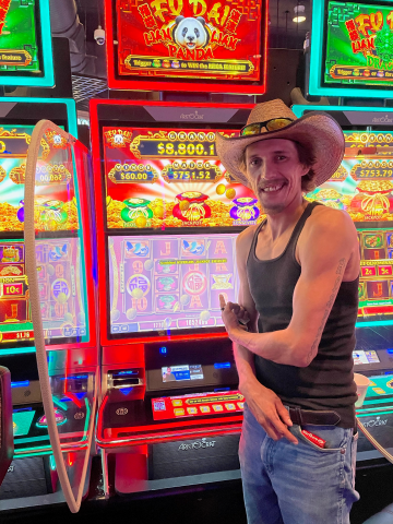 Austin S. standing in front of machine with $10,524.68 jackpot win.