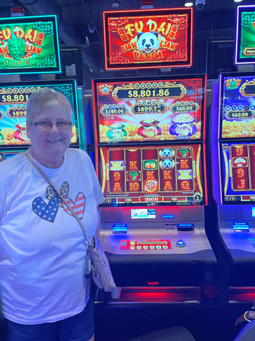 Beverly F. standing in front of machine with $10,542.34 jackpot win.