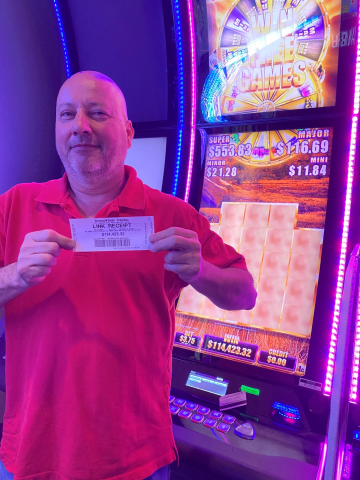 Carl M. holding a ticket for $114,423.32 jackpot win.