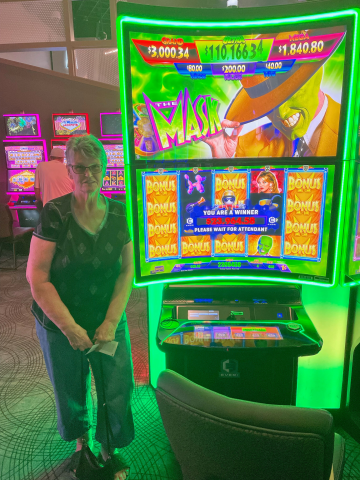 Connie D. standing in front of machine with $23,964.58 jackpot win.