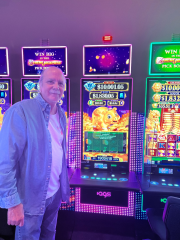 Gregory M. standing in front of machine with $19,034.18 jackpot win.