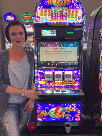 Shylah B. standing in front of machine with $12,000.00 jackpot win.