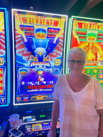 Terri M. standing in front of machine with $10,247.17 jackpot win.